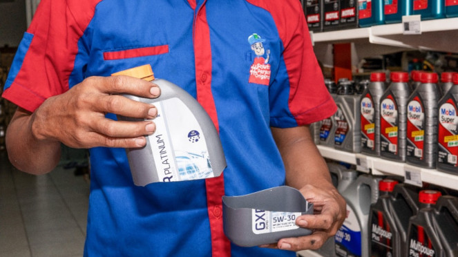 Mekanik memotong botol oli.