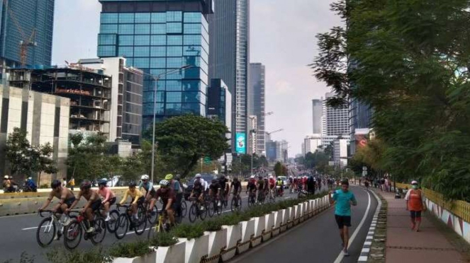 Gambar pengendara sepeda di jalan raya.