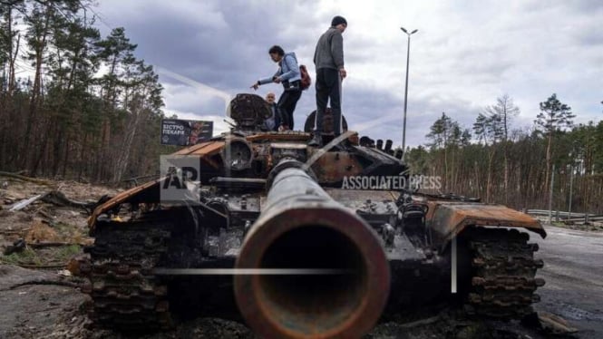Warga menaiki tank Rusia yang hancur dalam perang di Ukraina
