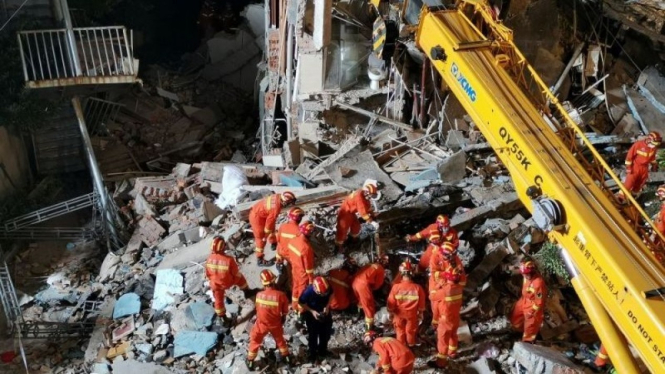 Petugas penyelamat mencari korban di reruntuhan bangunan yang ambruk di Suzhou, Jiangsu, China, 12 Juli 2021. 