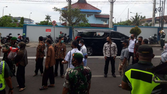 Presiden Joko Widodo (di dalam mobil Toyota Alphard) mengamati pembagian paket sembako kepada warga Kota Yogyakarta di Pasar Serangan pada Minggu, 1 Mei 2022.