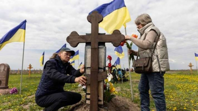 Sejumlah wanita Ukraina mengunjungi makam tentara kerabat mereka saat mengunjungi makam untuk menghormati kematian mereka pada hari Minggu pertama setelah Paskah di tengah serangan Rusia terhadap Ukraina, di Dnipro, Ukraina, Minggu, 1 Mei 2022.