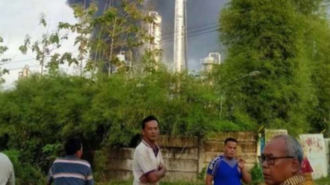 Sejumlah warga menyaksikan dari jauh peristiwa ledakan di areal operasional Stasiun Kompresor Gas (SKG) I Desa Kemang Tanduk, Kecamatan Rambang Kapak Tengah, Prabumulih, Sumatera Selatan, Senin, 9 Mei 2022.