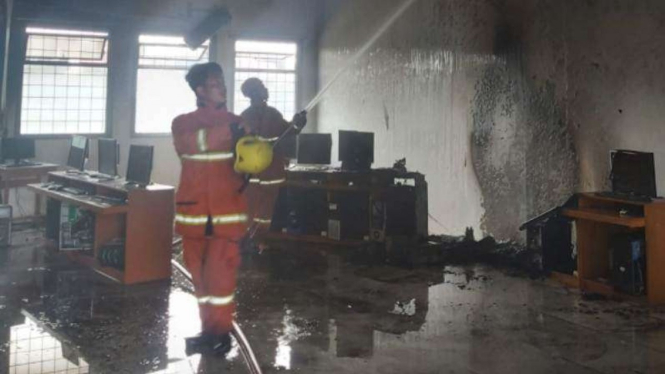 Petugas saat memadamkan api di lab komputer SMK Nasional, Limo.