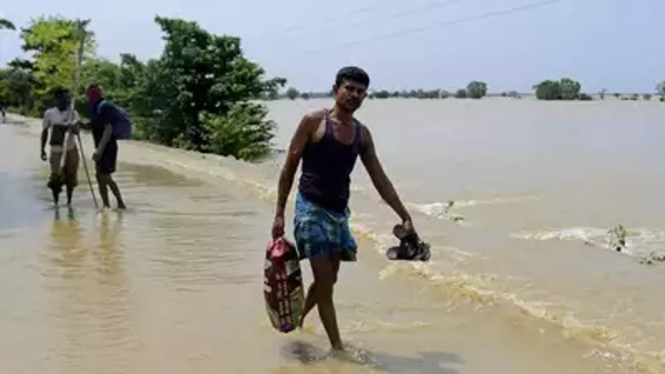 Orang-orang berjalan di area banjir, Assam, India.