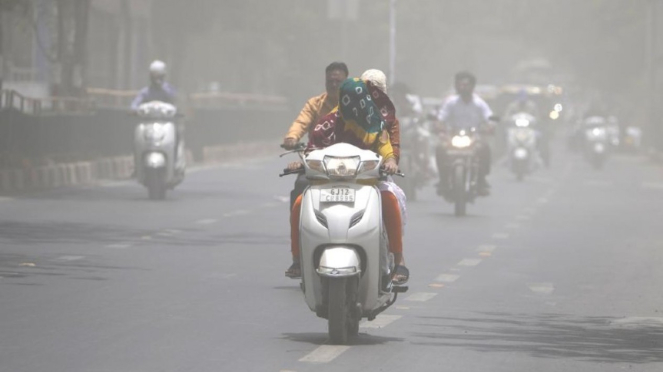 Un motociclista se cubre la cabeza con un trapo debido al calor que hace en la India.