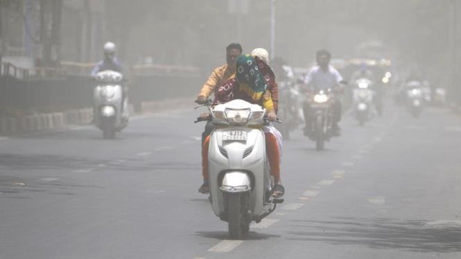 Seorang pengedara motor menutupi kepalanya dengan kain karena cuaca yang panas melanda India.