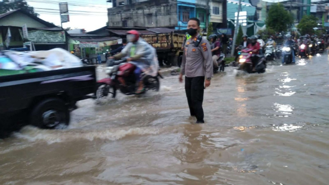 Polisi tengah mengatur lalu lintas di jalan yang tergenang banjir di Kota Jambi.