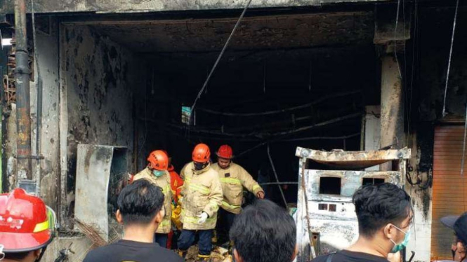 Petugas melakukan pembasahan di tokok kelontong yang terbakar di Wedoro, Waru.
