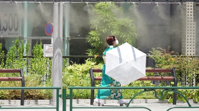 Seorang wanita berjalan dengan payung di tengah cuaca panas Kota Tokyo, Jepang