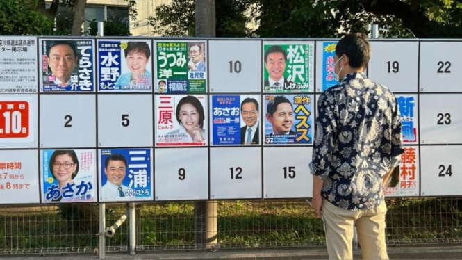 Seorang calon pemilih melihat papan yang menampilkan foto calon anggota Majelis Tinggi Jepang.
