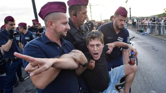 Petugas polisi berusaha menarik demonstran yang berunjuk rasa atas di Budapest