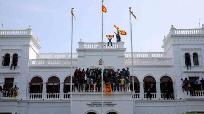Para pengunjuk rasa mengibarkan bendera Sri Lanka di atas gedung kantor Perdana Menteri Ranil Wickremesinghe.