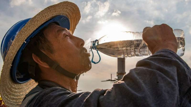 Pekerja proyek Chongqing Jiangbei, China minum air di tengah panas ekstrem