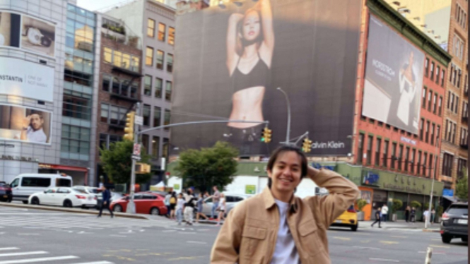Angga Yunanda bedpose di depan poster Jennie BLACKPINK di New York