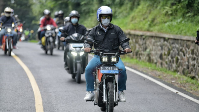 Gubernur Jawa Barat, Ridwan Kamil berwisata menggunakan sepeda motor listrik.