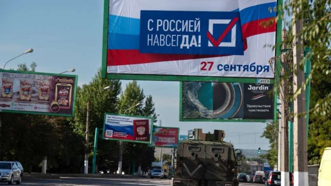 Tank melintas di jalan Luhansk dan tampak poster referendum dipasang