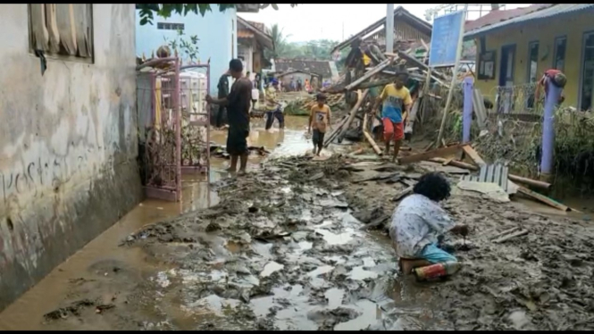 Warga membersihkan lumpur dari rumah usai banjir bandang di Garut.