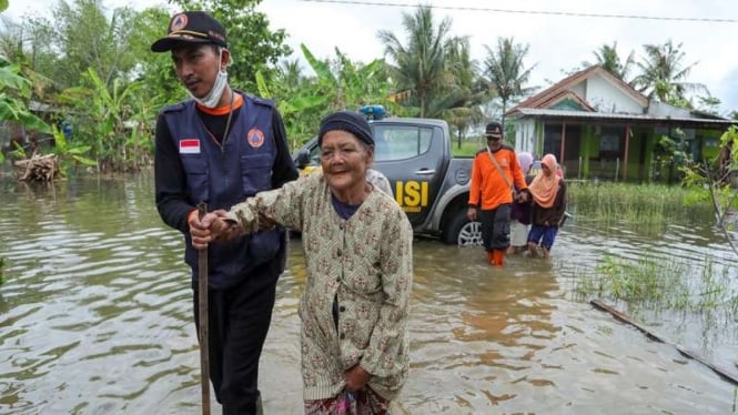 Relawan gabungan BPBD dan lain-lain, mengevakuasi warga yang terdampak banjir.