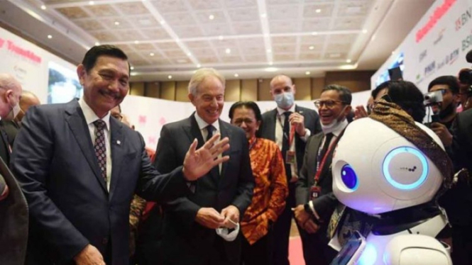 Menko Maritim dan Investasi Luhut Pandjaitan (kiri) dan mantan Perdana Menteri Inggris Tony Blair (kanan) berinteraksi dengan robot pintar saat mengunjungi area expo sebelum pembukaan State-Owned Enterprises (SOE) International Conference di Bali Nusa Dua