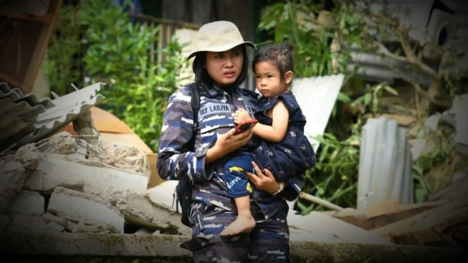 VIVA Militer: Prajurit Wanita TNI AL menggendong anak korban gempa.