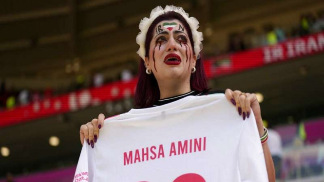 Suporter wanita Iran menunjukkan kaos dengan nama Mahsa Amini