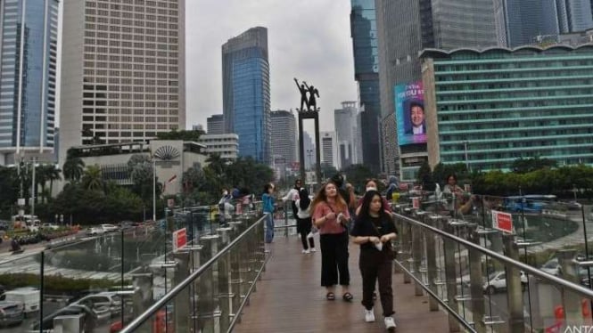 Sejumlah warga menikmati suasana Bundaran HI di anjungan Halte Bus Transjakarta.