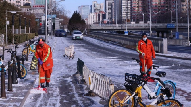 Petugas membersihkan salju yang menutupi permukaan jalan di ring road 3 Kota Beijing, China