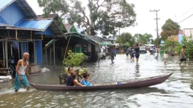 Warga menggunakan perahu melintasi jalan yang terendam banjir di Desa Sungai Rangas Ulu, Kabupaten Banjar, Kalimantan Selatan, Sabtu, 4 Maret 2023.