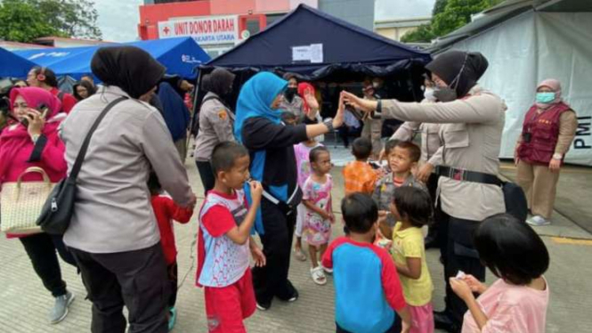 Sejumlah Polisi Wanita (Polwan) dan relawan menghibur para pengungsi korban kebakaran Depo Pertamina Plumpang di posko pengungsian PMI Jakarta Utara, Jakarta, Minggu, 5 Maret 2023.