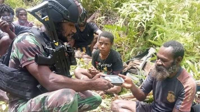 Prajurit TNI sedang membantu warga yang mengungsi ke Kenyam