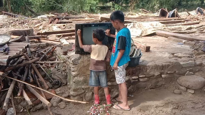 Anak-anak membersihkan televisi yang sempat terendam banjir bandang Sumbawa 