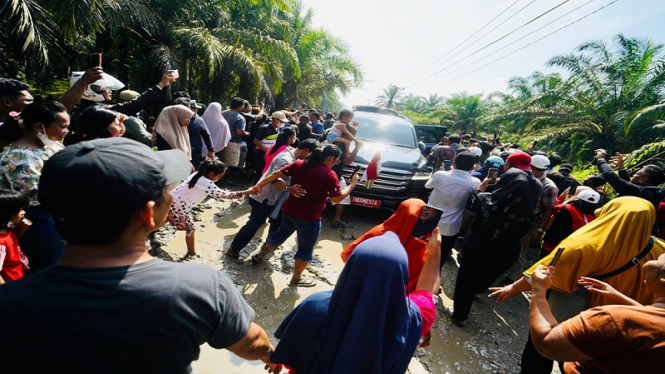 Mobil RI 1 yang melintasi jalan berkubang di Labura Sumut dikerubuti warga