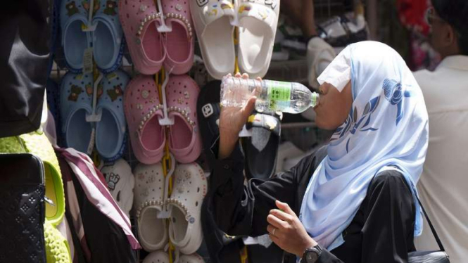 Wanita Malaysia tengah minum air di tengah gelombang panas di Kuala Lumpur