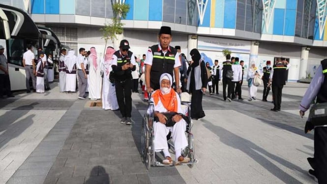 Petugas haji membantu jemaah haji dengan kursi roda di Bandara Madinah