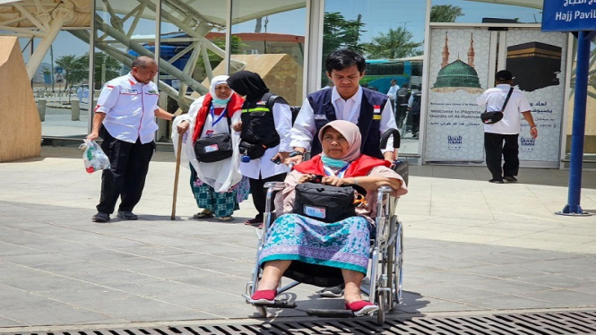 Petugas haji membantu jemaah haji dengan kursi roda di Bandara Madinah