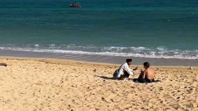 Seorang kakek terlihat merekam turis di Pantai Kuta Mandalika