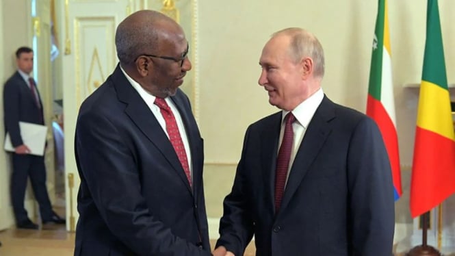 Presiden Rusia Vladimir Putin berjabat tangan dengan Ruhakana Rugunda, Utusan Khusus Presiden Uganda.