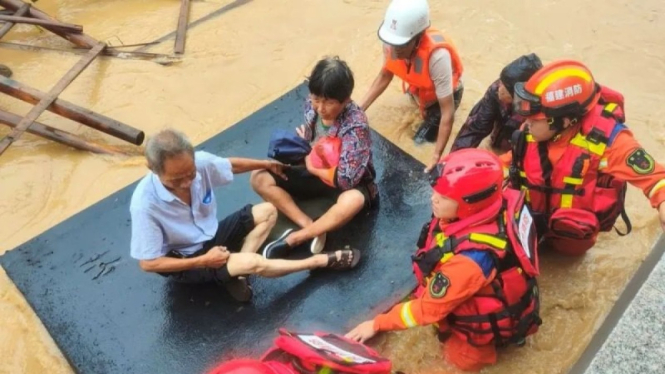 Petugas damkar mengevakuasi warga yang terjebak banjir disebabkan Topan Doksuri.