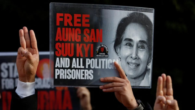 Para pengunjuk rasa Myanmar yang tinggal di Jepang mengangkat spanduk Aung San Suu Kyi sambil mengacungkan salam tiga jari.