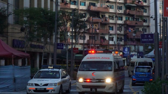 Sebuah ambulans didampingi mobil polisi di Malayan Mansion, Malaysia.