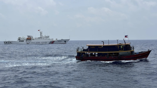 Sebuah kapal penjaga pantai Tiongkok berada dekat dengan kapal patroli Filipina di Laut Cina Selatan.