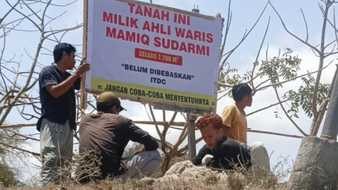 Seorang warga memasang pengumuman lahannya belum dibebaskan ITDC