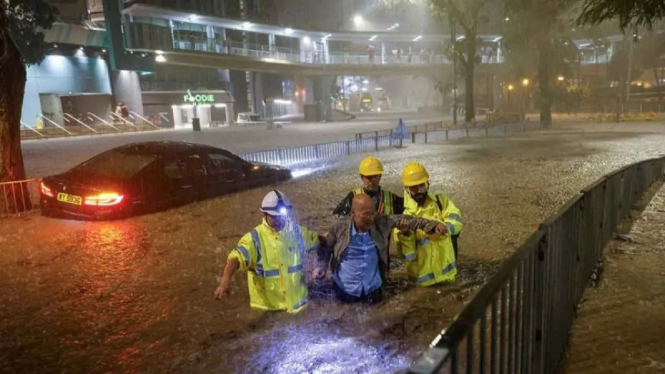 Pekerja drainase membantu pengemudi yang terjebak banjir saat hujan lebat di Hong Kong, Jumat (8/9/2023).