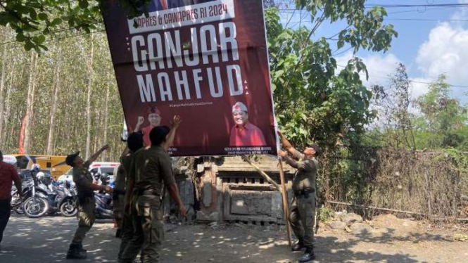 Aparat Satpol PP Bali saat menurunkan atribut partai politik PDIP di lokasi kunjungan kerja Presiden Joko Widodo di Pasar Bulan, Gianyar, Bali, Selasa, 31 Oktober 2023.