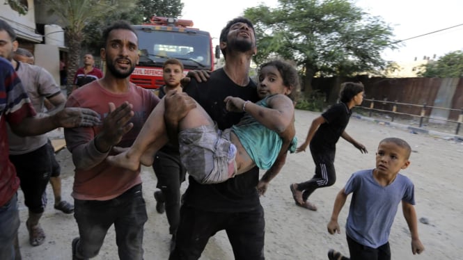 Seorang pria Palestina berusaha menyelamatkan anak perempuan yang terluka.