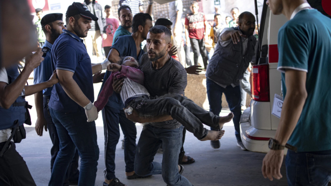 Pria Palestina membawa anak perempuan yang terluka ke rumah sakit.