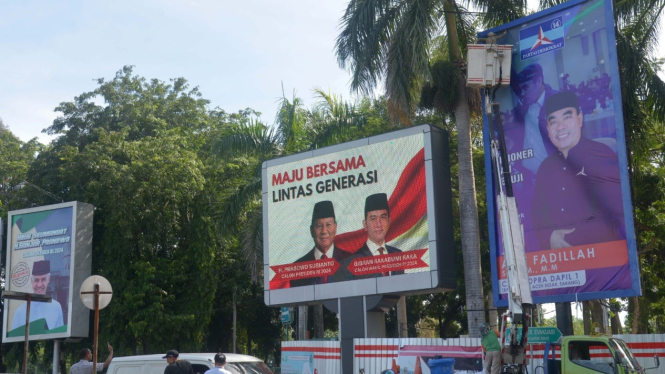 Petugas Panitia Pengawas Pemilihan Aceh menurunkan alat peraga kampanye
