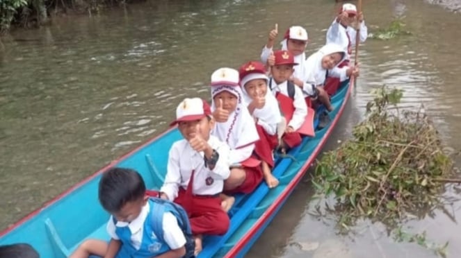 Los niños de la escuela primaria de Jambi cruzan el río Deras para ir a la escuela