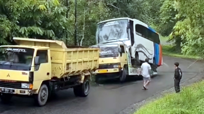 Truk gendong bus diderek dump truck
